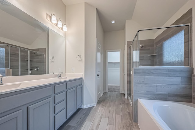 1111 Teamriddle Way, Richmond, TX 77406 - bathroom featuring a shower stall, double vanity, a bath, wood finished floors, and a walk in closet