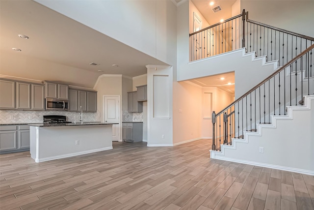 1111 Teamriddle Way, Richmond, TX 77406 - kitchen featuring gray cabinets, stainless steel microwave, range, backsplash, and light wood-style floors