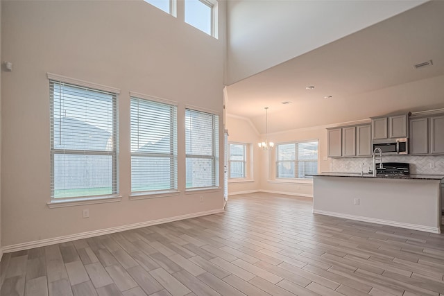 1111 Teamriddle Way, Richmond, TX 77406 - unfurnished living room featuring a chandelier, plenty of natural light, light wood-style floors, and a high ceiling