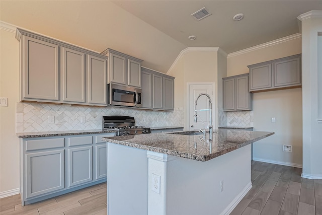 1111 Teamriddle Way, Richmond, TX 77406 - kitchen featuring stainless steel microwave, stove, wood finish floors, gray cabinets, and lofted ceiling