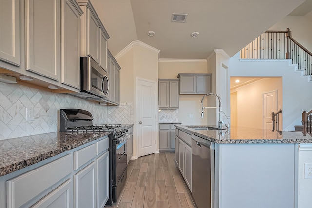 1111 Teamriddle Way, Richmond, TX 77406 - kitchen with appliances with stainless steel finishes, gray cabinetry, dark stone countertops, ornamental molding, and light wood-style floors