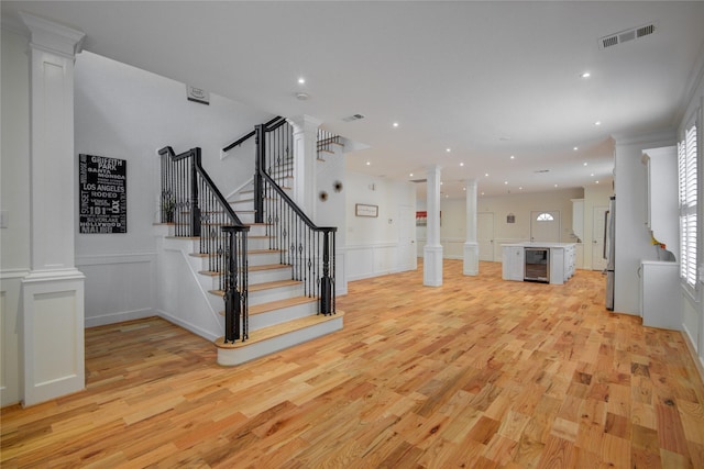 4400 Edith St, Bellaire, TX 77401 - unfurnished living room with decorative columns, a decorative wall, light wood-type flooring, stairs, and recessed lighting