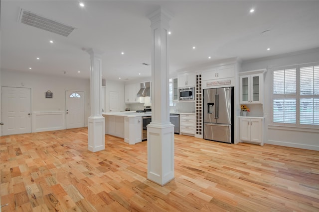 4400 Edith St, Bellaire, TX 77401 - kitchen with decorative columns, stainless steel appliances, light wood finished floors, a center island, and white cabinetry