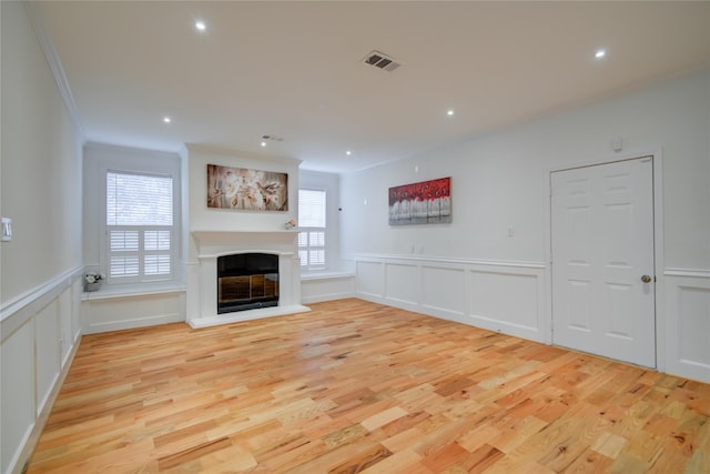 4400 Edith St, Bellaire, TX 77401 - unfurnished living room featuring light wood-style floors, a decorative wall, a glass covered fireplace, recessed lighting, and ornamental molding