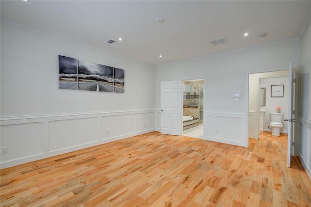 4400 Edith St, Bellaire, TX 77401 - unfurnished bedroom featuring crown molding, connected bathroom, a decorative wall, light wood-type flooring, and a wainscoted wall