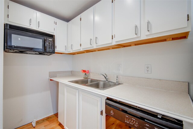 4400 Edith St, Bellaire, TX 77401 - kitchen with black appliances, light countertops, light wood-style flooring, and white cabinets