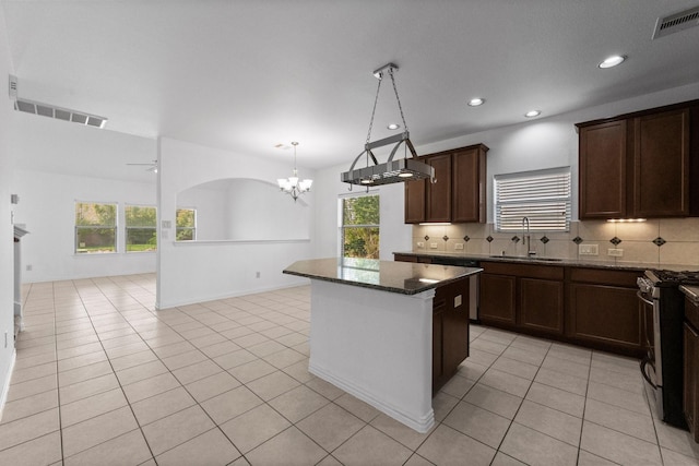 22303 Mosshall Ct, Tomball, TX 77375 - kitchen featuring stainless steel gas range, a chandelier, tasteful backsplash, a center island, and dark stone countertops