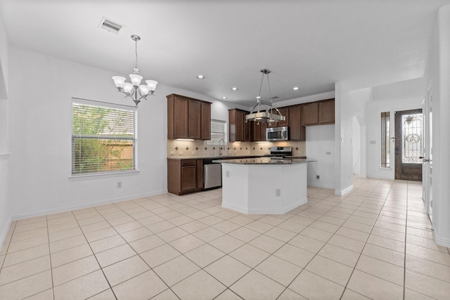22303 Mosshall Ct, Tomball, TX 77375 - kitchen with appliances with stainless steel finishes, a chandelier, backsplash, dark countertops, and pendant lighting