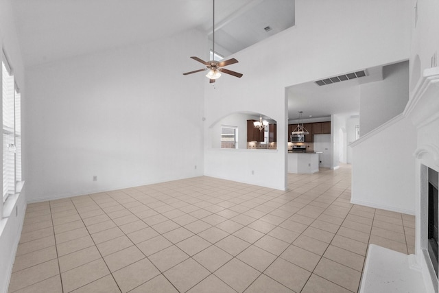 22303 Mosshall Ct, Tomball, TX 77375 - unfurnished living room with ceiling fan, light tile patterned floors, high vaulted ceiling, a chandelier, and arched walkways