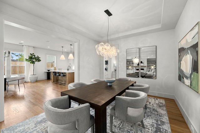 4902 Oak Forest Dr, Houston, TX 77018 - dining space with a chandelier, light wood-style flooring, and a tray ceiling