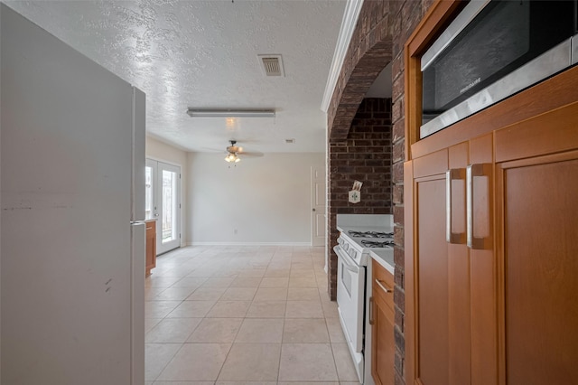 21319 Park Mill Dr, Katy, TX 77450 - kitchen featuring white appliances, a textured ceiling, a ceiling fan, light tile patterned floors, and brown cabinetry