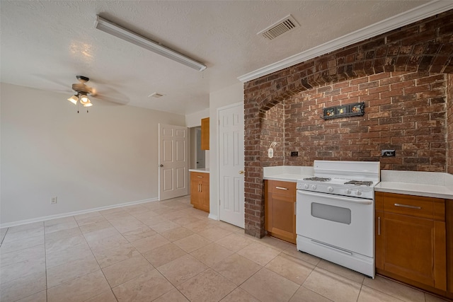 21319 Park Mill Dr, Katy, TX 77450 - kitchen featuring white gas range oven, brown cabinets, a ceiling fan, a textured ceiling, and light countertops