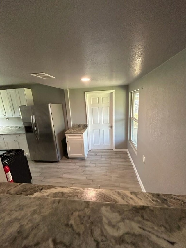 1108 Niagara St, Houston, TX 77051 - kitchen featuring stainless steel refrigerator with ice dispenser, gas stove, white cabinets, a textured ceiling, and light wood finished floors