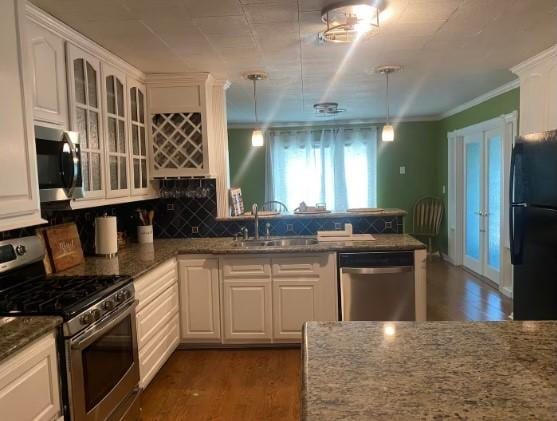 160 E Darby St, Bridge City, TX 77611 - kitchen featuring appliances with stainless steel finishes, glass insert cabinets, dark wood finished floors, white cabinetry, and tasteful backsplash