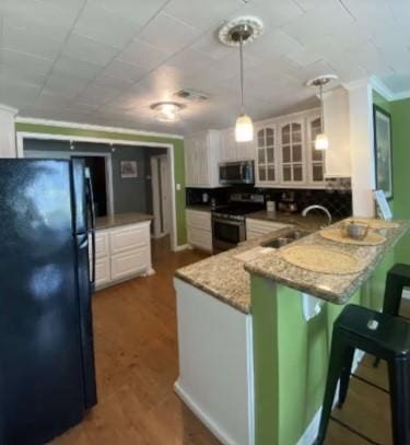160 E Darby St, Bridge City, TX 77611 - kitchen with stainless steel appliances, a peninsula, a kitchen bar, white cabinetry, and ornamental molding