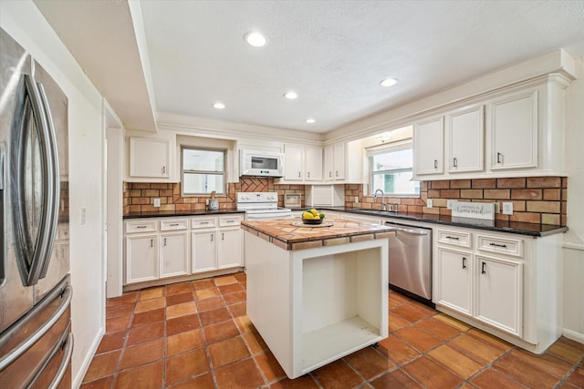 33410 Cripple Creek Dr, Pinehurst, TX 77362 - kitchen with stainless steel appliances, backsplash, a center island, white cabinets, and recessed lighting