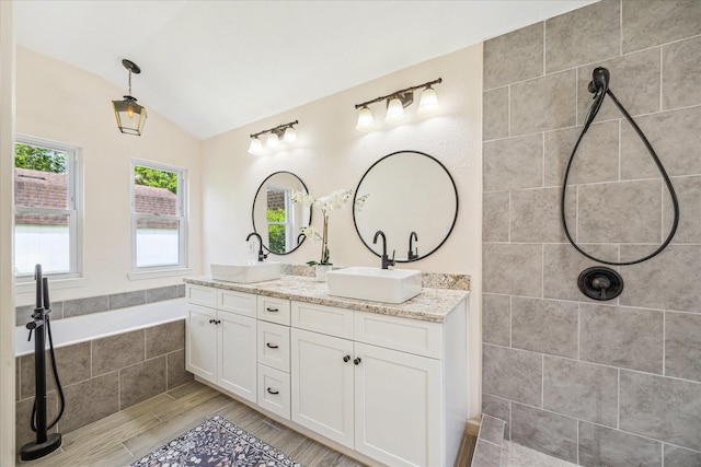 33410 Cripple Creek Dr, Pinehurst, TX 77362 - bathroom with double vanity, vaulted ceiling, a tile shower, a bath, and wood finished floors