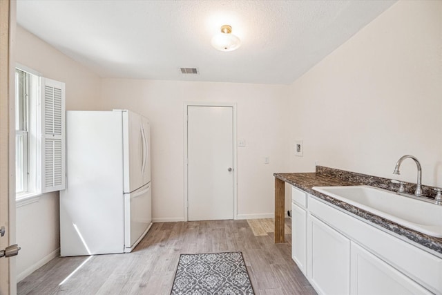 33410 Cripple Creek Dr, Pinehurst, TX 77362 - kitchen featuring freestanding refrigerator, light wood finished floors, white cabinetry, and dark countertops