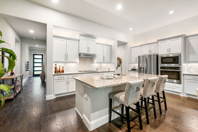 27688 Vivace Dr, Spring, TX 77386 - kitchen featuring appliances with stainless steel finishes, light stone countertops, decorative backsplash, an island with sink, and recessed lighting
