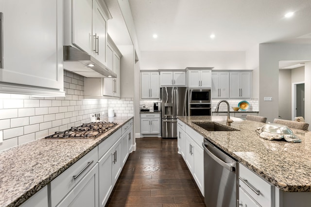 27688 Vivace Dr, Spring, TX 77386 - kitchen with stainless steel appliances, under cabinet range hood, tasteful backsplash, dark wood finished floors, and a kitchen island with sink