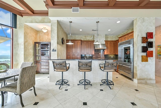4821 Nasa Pkwy Unit 18W, Seabrook, TX 77586 - kitchen with stainless steel built in refrigerator, wall chimney range hood, dark countertops, a breakfast bar, and ornamental molding