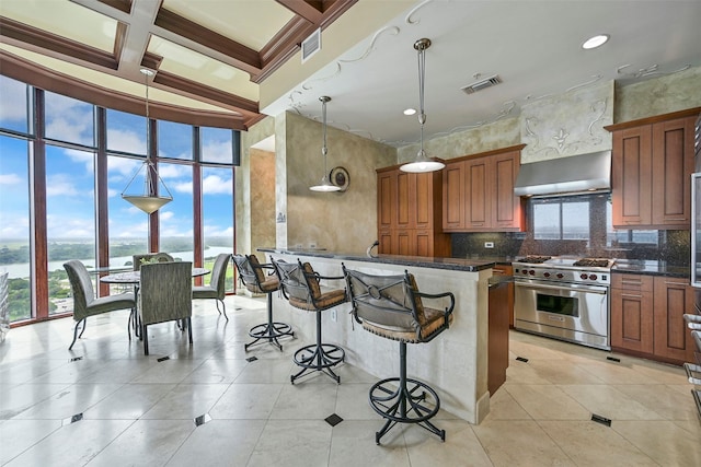 4821 Nasa Pkwy Unit 18W, Seabrook, TX 77586 - kitchen featuring premium range, wall chimney range hood, a kitchen bar, brown cabinets, and decorative backsplash