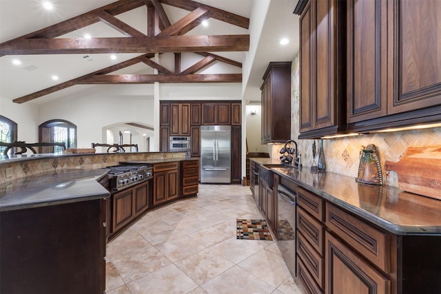 19216 Fm 442nd Rd, Needville, TX 77461 - kitchen featuring appliances with stainless steel finishes, tasteful backsplash, light tile patterned floors, dark brown cabinets, and a large island with sink