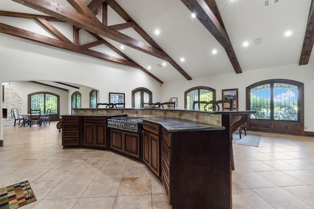 19216 Fm 442nd Rd, Needville, TX 77461 - kitchen featuring dark countertops, a kitchen breakfast bar, stainless steel gas stovetop, beamed ceiling, and recessed lighting