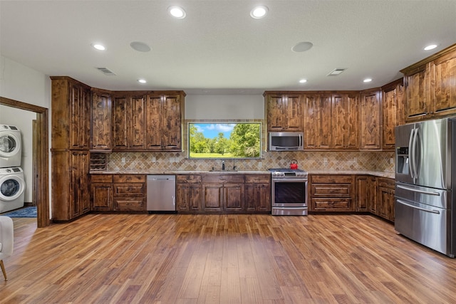 19216 Fm 442nd Rd, Needville, TX 77461 - kitchen featuring stainless steel appliances, stacked washing machine and dryer, wood finished floors, backsplash, and recessed lighting