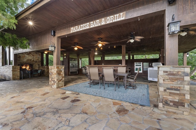 19216 Fm 442nd Rd, Needville, TX 77461 - view of patio featuring an outdoor stone fireplace, a ceiling fan, and an outdoor kitchen