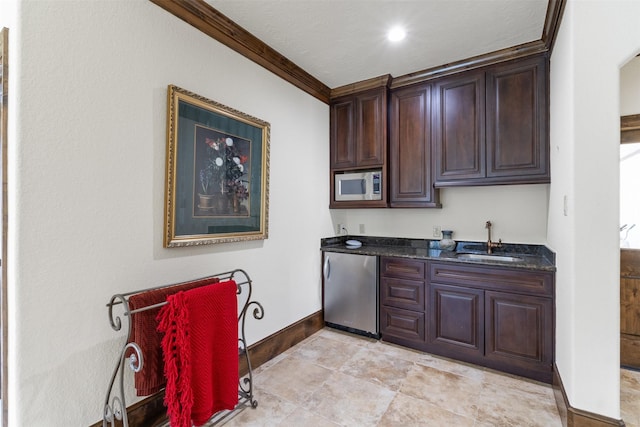 19216 Fm 442nd Rd, Needville, TX 77461 - kitchen with fridge, stainless steel microwave, dark brown cabinets, dark stone counters, and ornamental molding