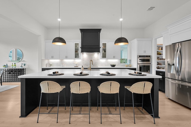 5212 Liberty Cove Dr, Spring, TX 77386 - kitchen featuring appliances with stainless steel finishes, backsplash, light countertops, a large island with sink, and a breakfast bar