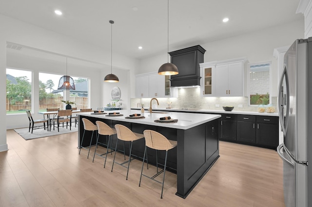 5212 Liberty Cove Dr, Spring, TX 77386 - kitchen with freestanding refrigerator, white cabinetry, decorative backsplash, a kitchen bar, and dark cabinets