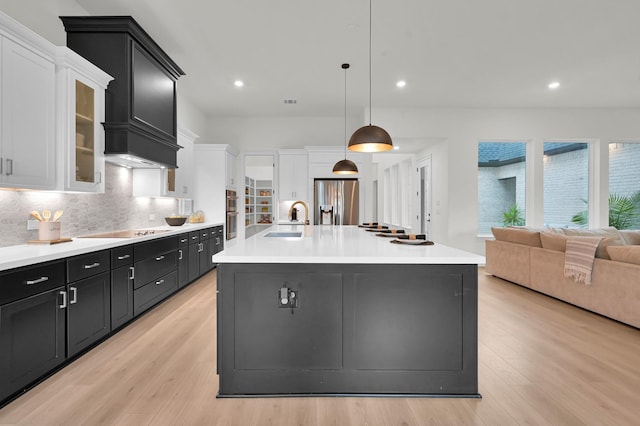 5212 Liberty Cove Dr, Spring, TX 77386 - kitchen with stainless steel appliances, dark cabinets, light countertops, tasteful backsplash, and light wood-style flooring