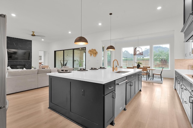 5212 Liberty Cove Dr, Spring, TX 77386 - kitchen featuring stainless steel dishwasher, light countertops, light wood-type flooring, recessed lighting, and an island with sink