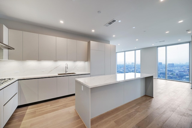 1711 Allen Pkwy Unit 2203, Houston, TX 77019 - kitchen with modern cabinets, light wood-style flooring, a wall of windows, a kitchen island, and backsplash