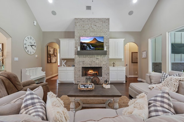 115 Dedication Trl, Huntsville, TX 77340 - living area with arched walkways, high vaulted ceiling, a brick fireplace, and dark wood finished floors