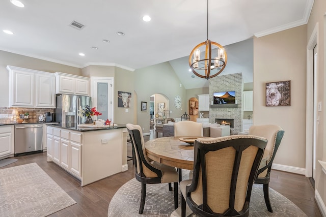 115 Dedication Trl, Huntsville, TX 77340 - dining area with arched walkways, a chandelier, recessed lighting, a fireplace, and dark wood-style flooring