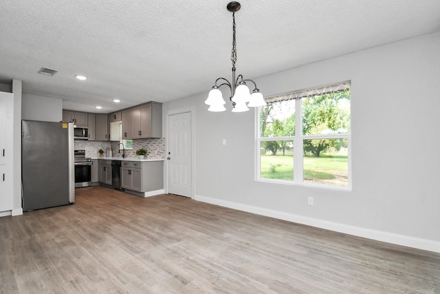 1030 San Felipe Rd, Sealy, TX 77474 - kitchen with stainless steel appliances, gray cabinets, light countertops, a chandelier, and wood finished floors