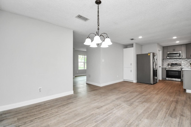 1030 San Felipe Rd, Sealy, TX 77474 - unfurnished living room featuring light wood finished floors, a textured ceiling, a chandelier, and recessed lighting