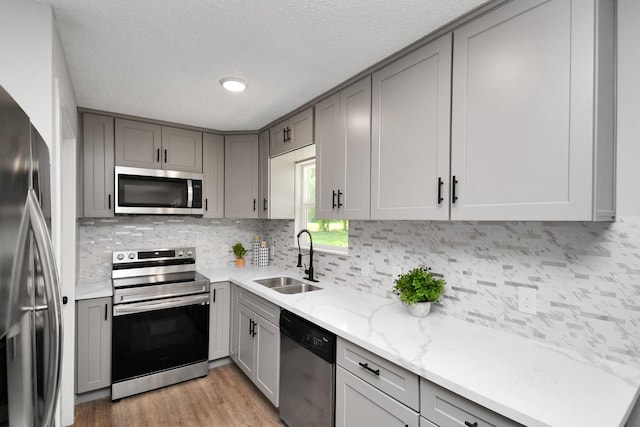 1030 San Felipe Rd, Sealy, TX 77474 - kitchen with appliances with stainless steel finishes, gray cabinetry, backsplash, light stone counters, and a textured ceiling