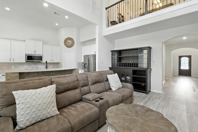 16413 Stonewall St, Conroe, TX 77303 - living room featuring a towering ceiling, arched walkways, light wood-type flooring, and recessed lighting