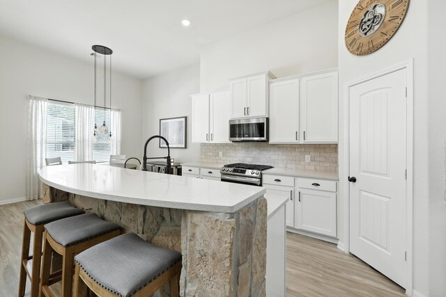 16413 Stonewall St, Conroe, TX 77303 - kitchen featuring appliances with stainless steel finishes, decorative backsplash, light wood finished floors, a breakfast bar area, and recessed lighting
