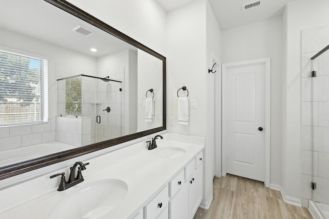 16413 Stonewall St, Conroe, TX 77303 - full bathroom with a stall shower, double vanity, wood finished floors, and a tub to relax in