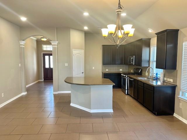 19522 Brighton Brook Ln, Richmond, TX 77407 - kitchen featuring stainless steel appliances, arched walkways, decorative columns, backsplash, and a kitchen island