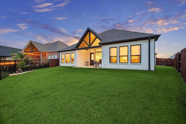 631 Rita Blanca Dr, Webster, TX 77598 - back of property at dusk with a fenced backyard, roof with shingles, a patio, and brick siding
