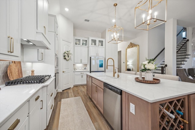 631 Rita Blanca Dr, Webster, TX 77598 - kitchen with appliances with stainless steel finishes, light wood finished floors, a chandelier, a center island with sink, and white cabinets