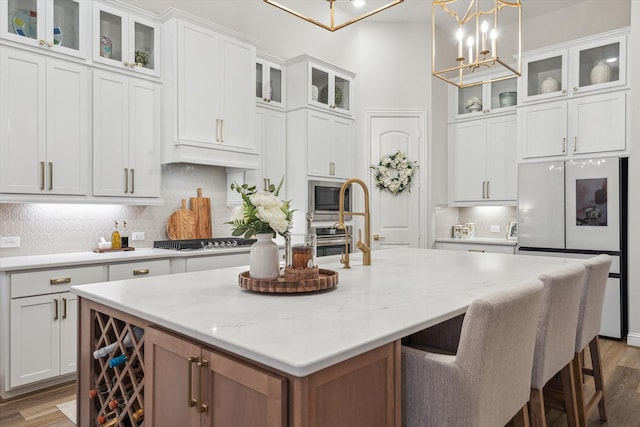 631 Rita Blanca Dr, Webster, TX 77598 - kitchen featuring stainless steel appliances, an island with sink, light wood-type flooring, and decorative backsplash