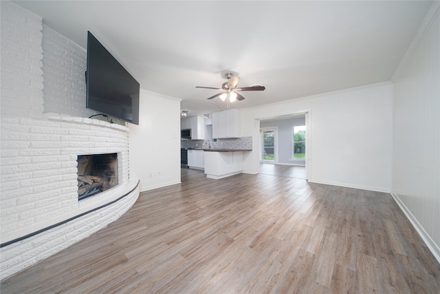7602 Jackwood St, Houston, TX 77074 - unfurnished living room featuring wood finished floors, ceiling fan, crown molding, and a brick fireplace