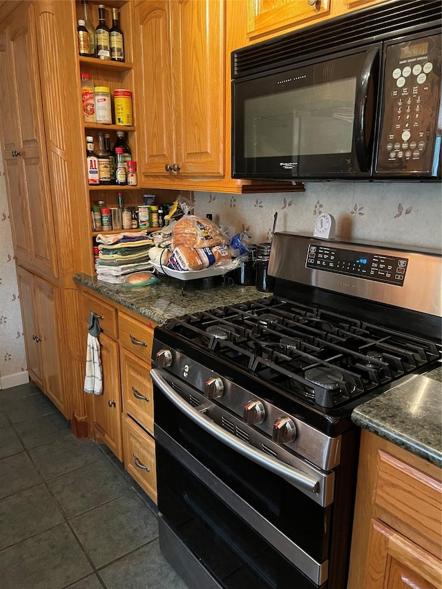 507 Oak Dr, Lake Jackson, TX 77566 - kitchen with stainless steel gas stove, black microwave, dark tile patterned floors, brown cabinetry, and open shelves